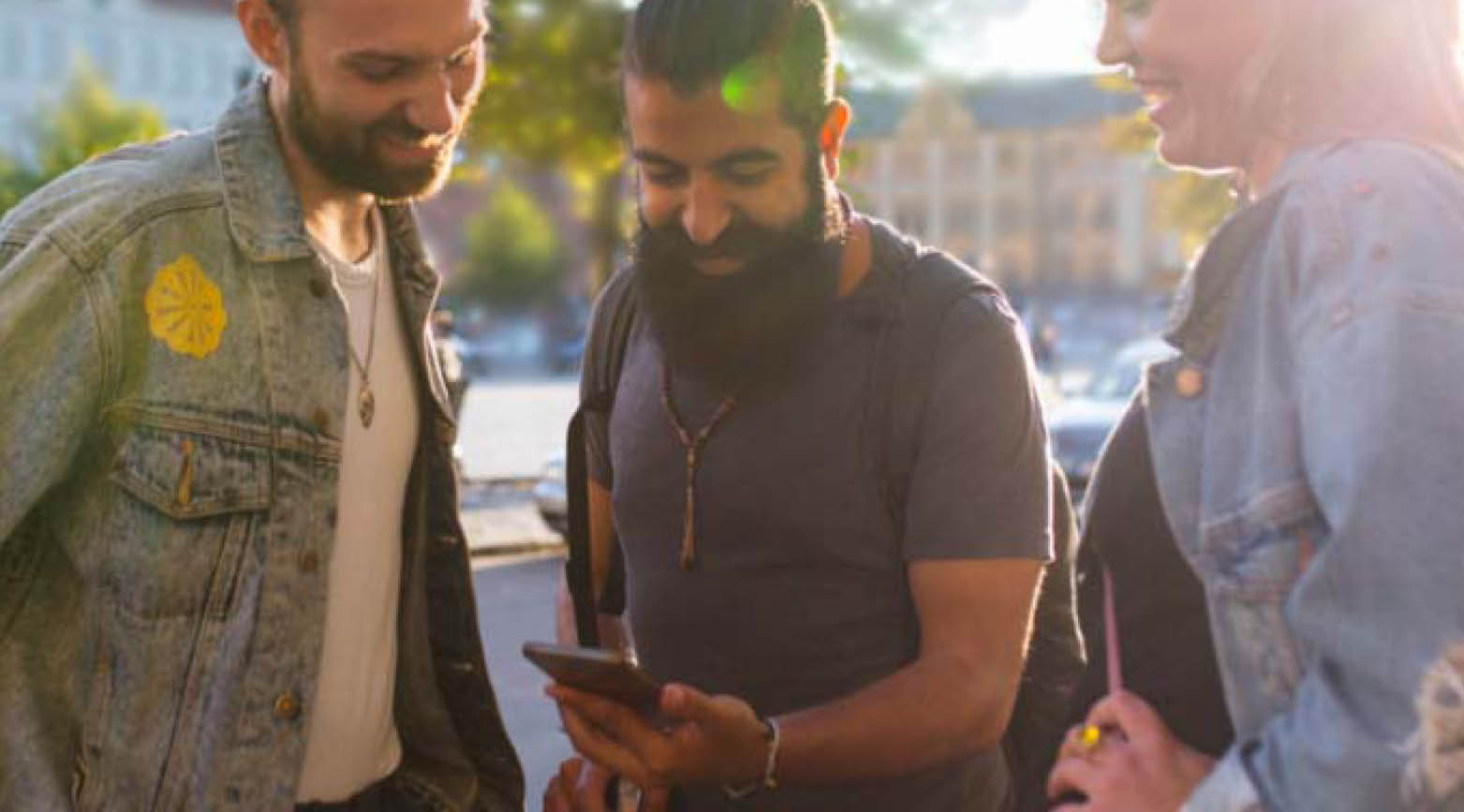 Bild över tre personer som tittar på en telefon