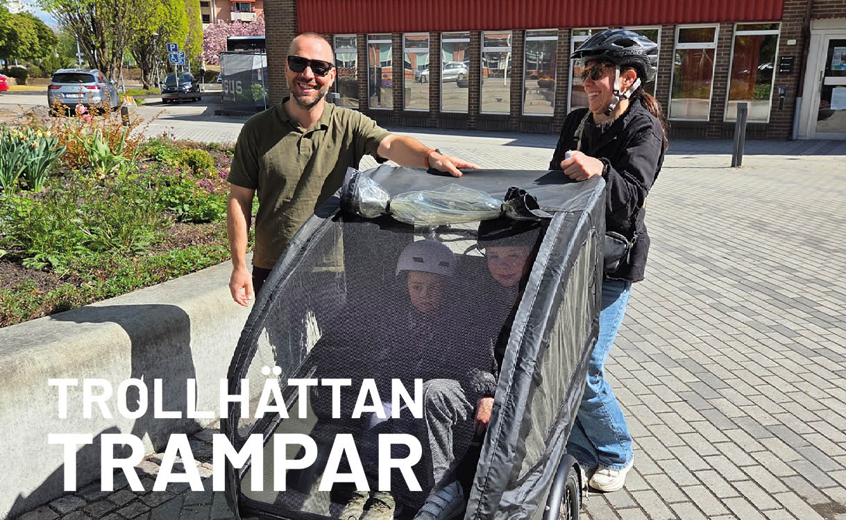 Man och kvinna bakom ellådcykel med barn i lådan. 