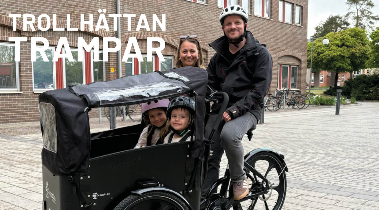 Man och och kvinna bakom ellådcykel med två barn i.