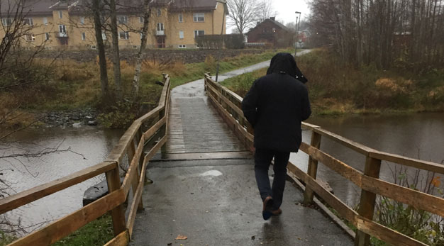 En man i mörka kläder går på en gång- och cykelbro