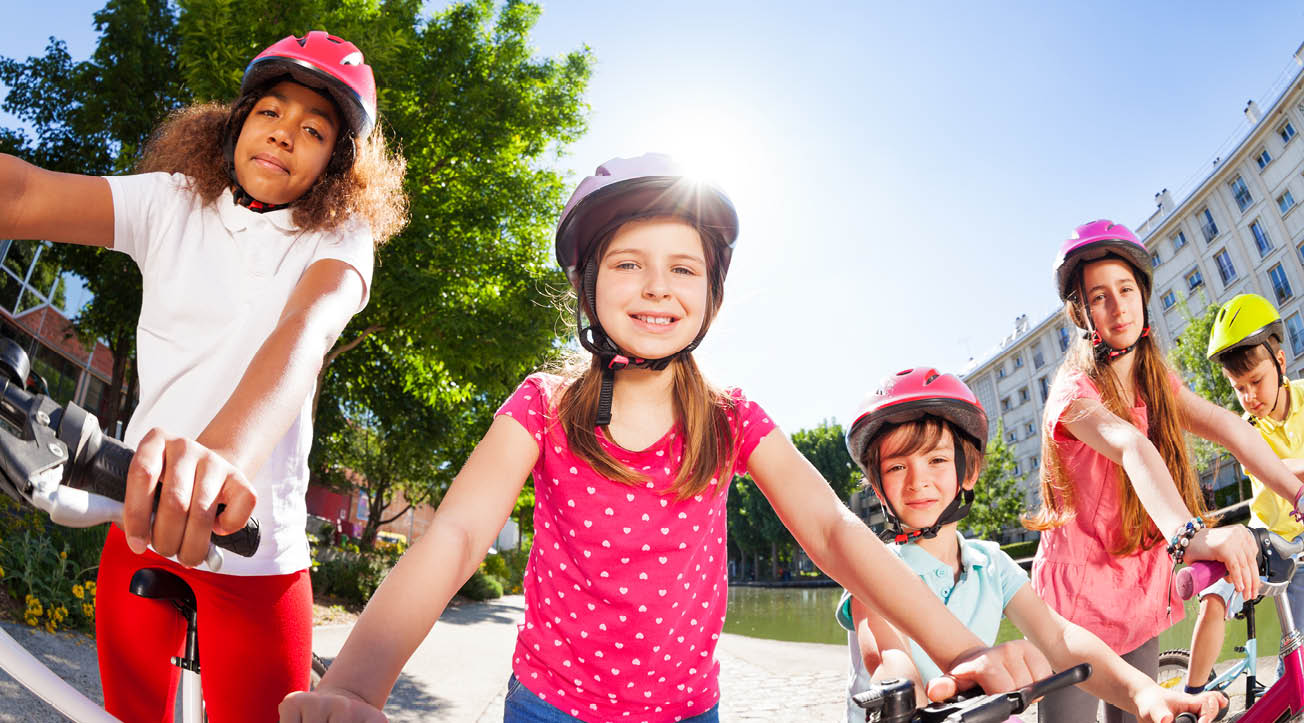 Glada barn med hjälmar och cyklar