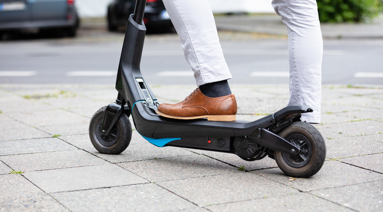 Man med elsparkcykel står på gatan