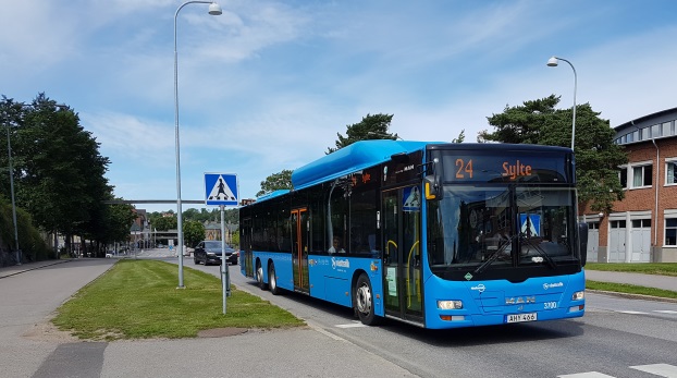 Buss på en gata, till vänster syns gång- och cykelbana. På bussen står det 24 Sylte.