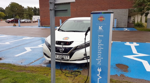 Elbil som laddas, laddstolpen syns framför bilen.