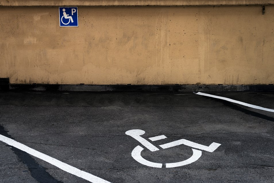 Ett ljusblått parkeringstillstånd för rörelsehindrad och en p-skiva med en vy från Trollhättan