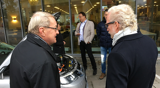 De olika aktörerna, Högskolan Väst, Trollhättans Stad och NEVS, samlade framför en av de elbilar som kommer att ingå i projektet.