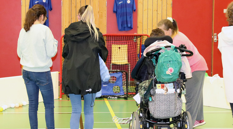 Person i rullstol testar innebandy. Runt omkring står personer och tittar på.