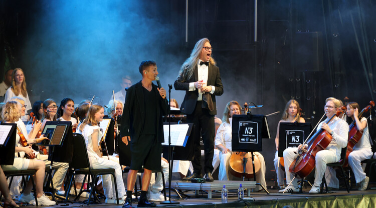 Artisten Daniel Adams-Ray uppträder på scen med orkester