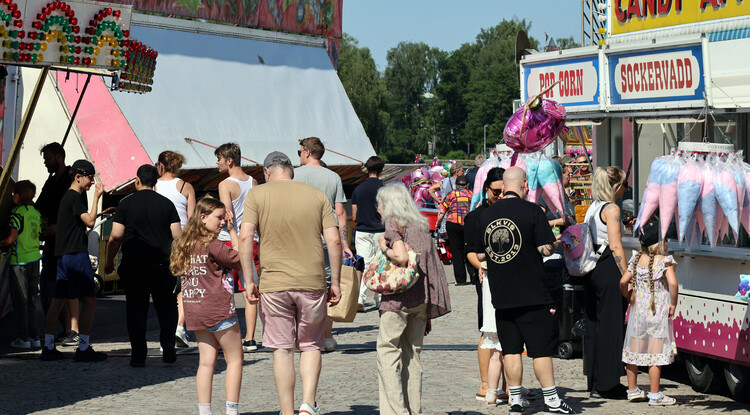 Personer strosar runt vid tivoli.
