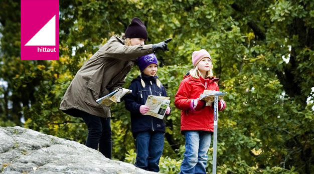 Två barn och en vuxen använder kartan Hitta ut