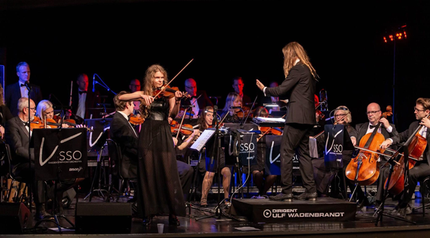 En symfoniorkester spelar. Första violinisten står upp och spelar.