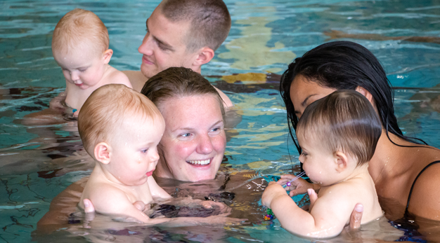 Bebisar och vuxna i simbassäng.