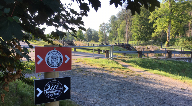 Skyltar som visar löparloppen Kraftprovet och Trollhättan City Trail. I bakgrunden syns slussarna.