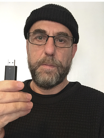 En man håller upp sitt bidrag till Öppen salong 2020, ett usb på tolkning av temat skog.