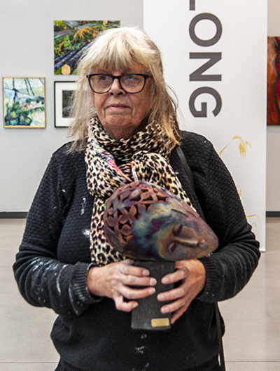 En kvinna håller upp sitt bidrag till Öppen salong 2020, en skulptur som tolkar temat skog.