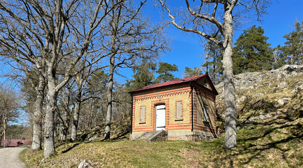 Gammal arkivbyggnad i tegel i en skogsdunge