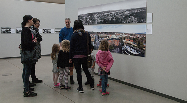 En familj tittar på en bild som visar en vy över staden Trollhättan