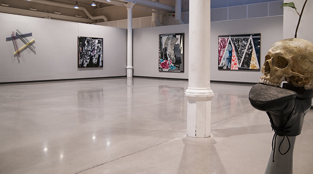 Kosnthallens utställningslokal med ett kranie i förgrunden och tavlor i bakgrunden. 