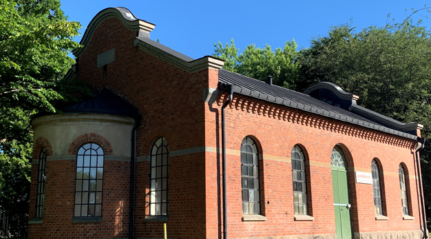 Tegelbyggnad från 1800-talet med många stora fönster.
