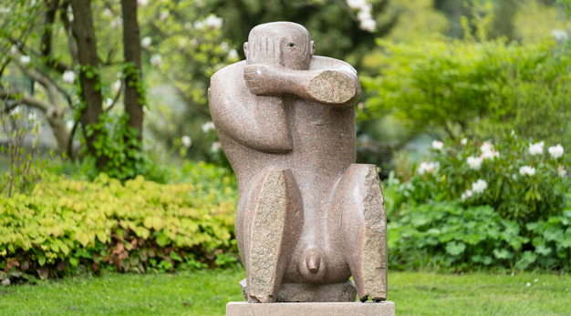 Skulptur i forma av en  manlig gestalt sitter och håller en hand framför ett öga.