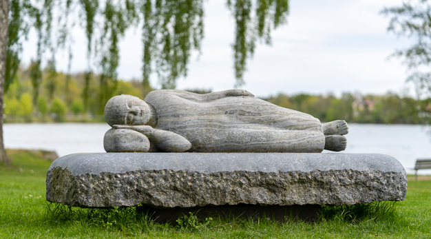 Liggande gestalt på stenbädd.