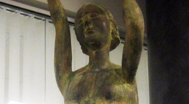 Ballerina i brons som sträcker upp armarna ovan huvudet.