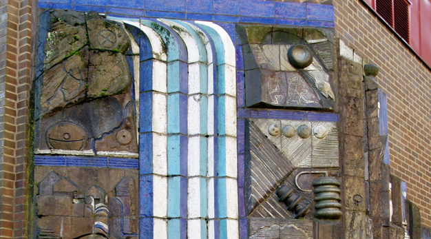 En relief i stengodslera som är placerad på stadhusets tegelfasad.