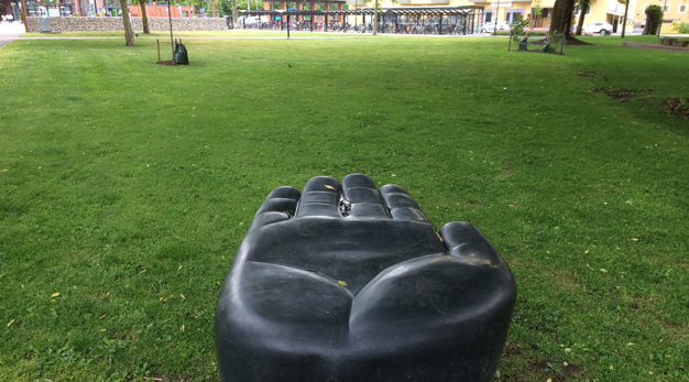 En skulptur i form av en svart hand står på en gräsmatta.