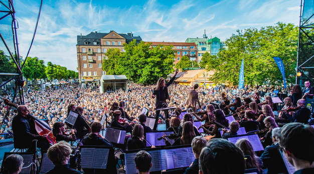 Bild tagen från bakdelen av scenen och fångar symfoniorkester och ett publikhav på Drottningtorget. 