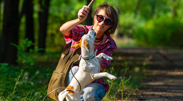 En kvinna med solglasögon leker med en hund. 