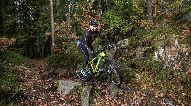 En man cyklar mountainbike i skogen. 