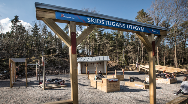 Utegym byggt till stor del i trä. Skog i bakgrunden. 