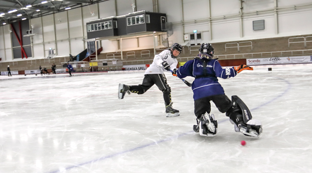 Två tjejer spelar isbandy.
