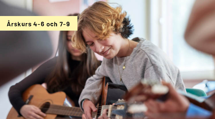Kille som spelar gitarr under musiklektion.