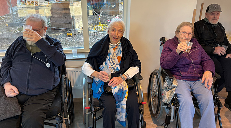 Tre äldre i rullstolar dricker bubbel