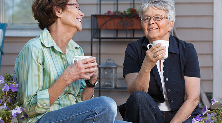 Två kvinnor sitter ute och dricker kaffe