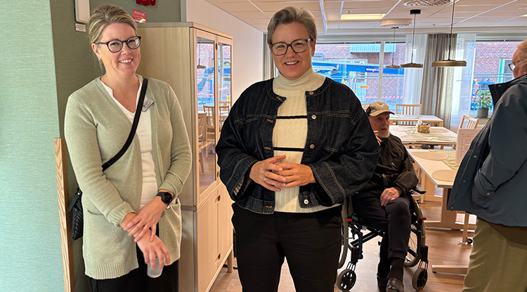 Två kvinnor med cider i glaset tittar in i kameran