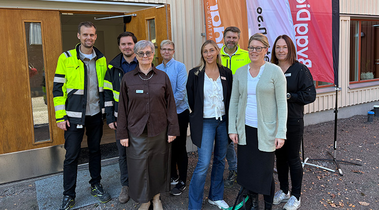En grupp av människor framför en dörr med beachflaggor bakom